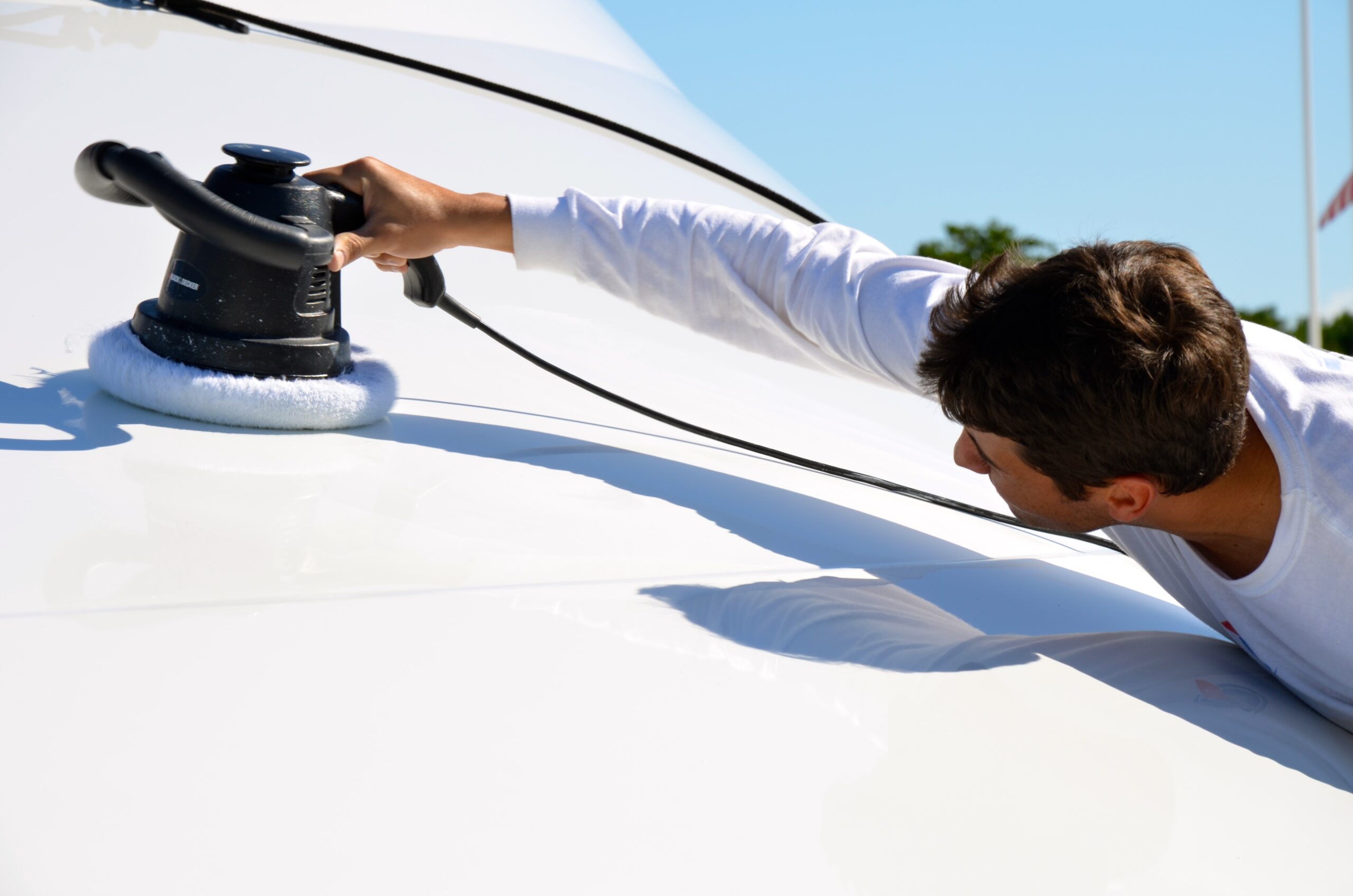 Man polishing boat with electric buffer tool.